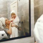 Family in a bathroom. Beautiful mother with little son. Little boy brush his teeth.