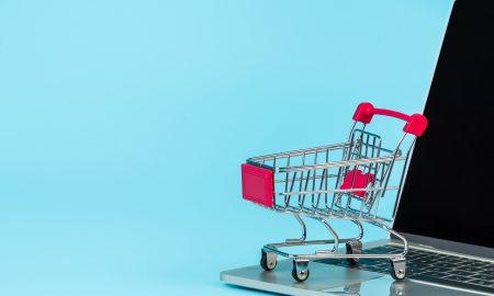 Online shopping concept, a shopping cart placed alongside a notebook on a blue background.