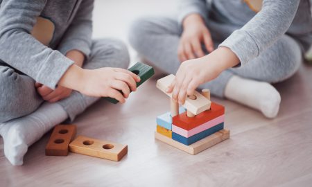 Children play with a toy designer on the floor of the children's room. Two kids playing with colorful blocks. Kindergarten educational games. Close up view.