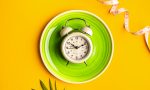 Composition with plate, alarm clock and measuring tape on a colored background. Diet concept and weight loss plan.