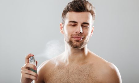 Portrait of a handsome half naked man spraying perfume