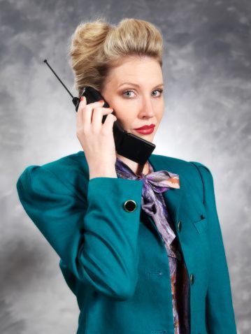 Business woman in 80’s power suit on old mobile phone_