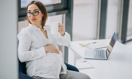 Young pregnant business woman working on computer at the office