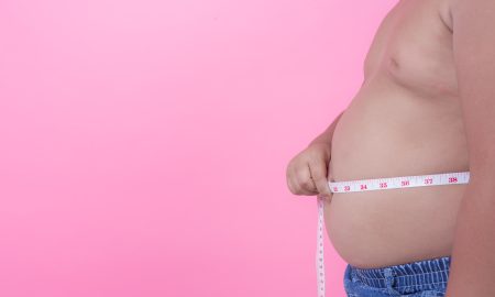 Obese boy who is overweight on a pink background.